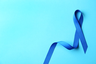 Photo of Blue ribbon on color background, top view with space for text. Colon cancer awareness concept