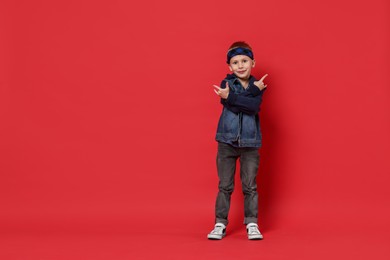 Photo of Happy little boy dancing on red background