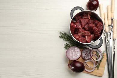 Photo of Composition with metal skewers and fresh meat on white wooden table, flat lay. Space for text