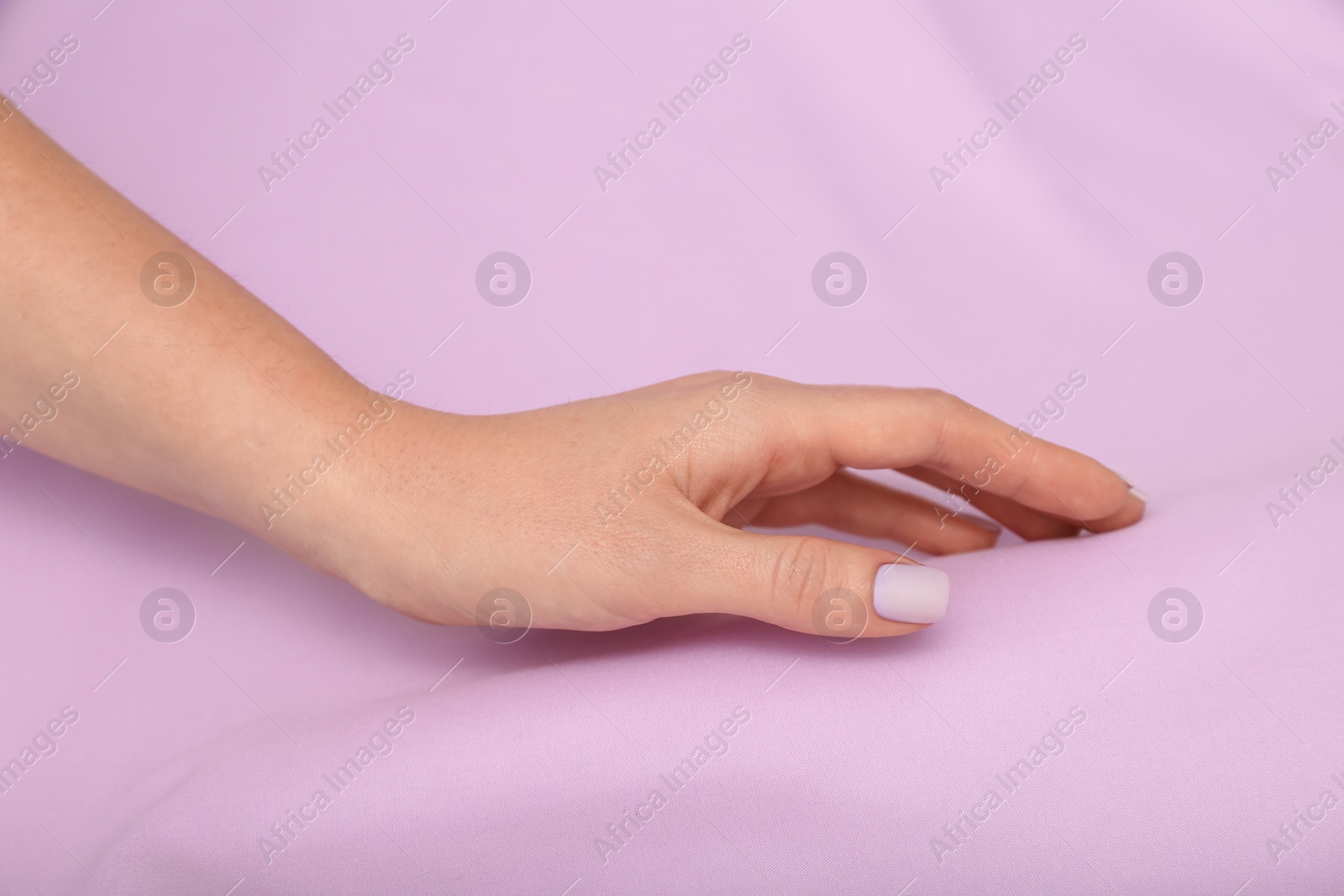 Photo of Woman touching soft violet fabric, closeup of hand