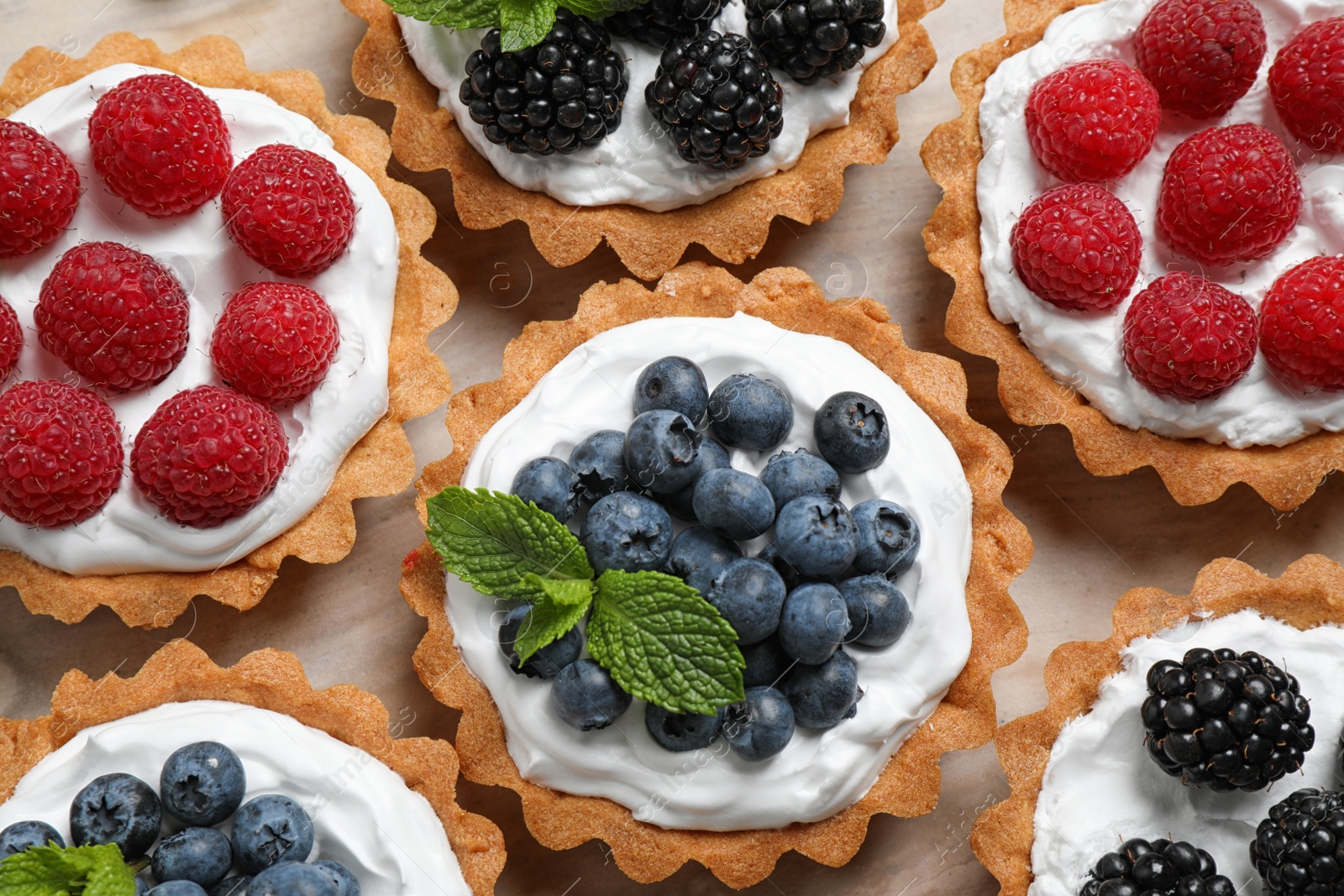 Photo of Many different berry tarts on table, top view. Delicious pastries