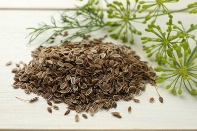 Photo of Dry seeds and fresh dill on white wooden table, closeup