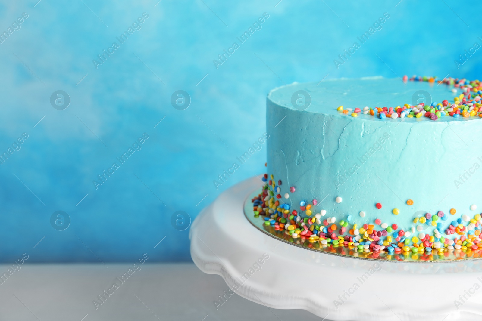 Photo of Fresh delicious birthday cake on stand against color background. Space for text