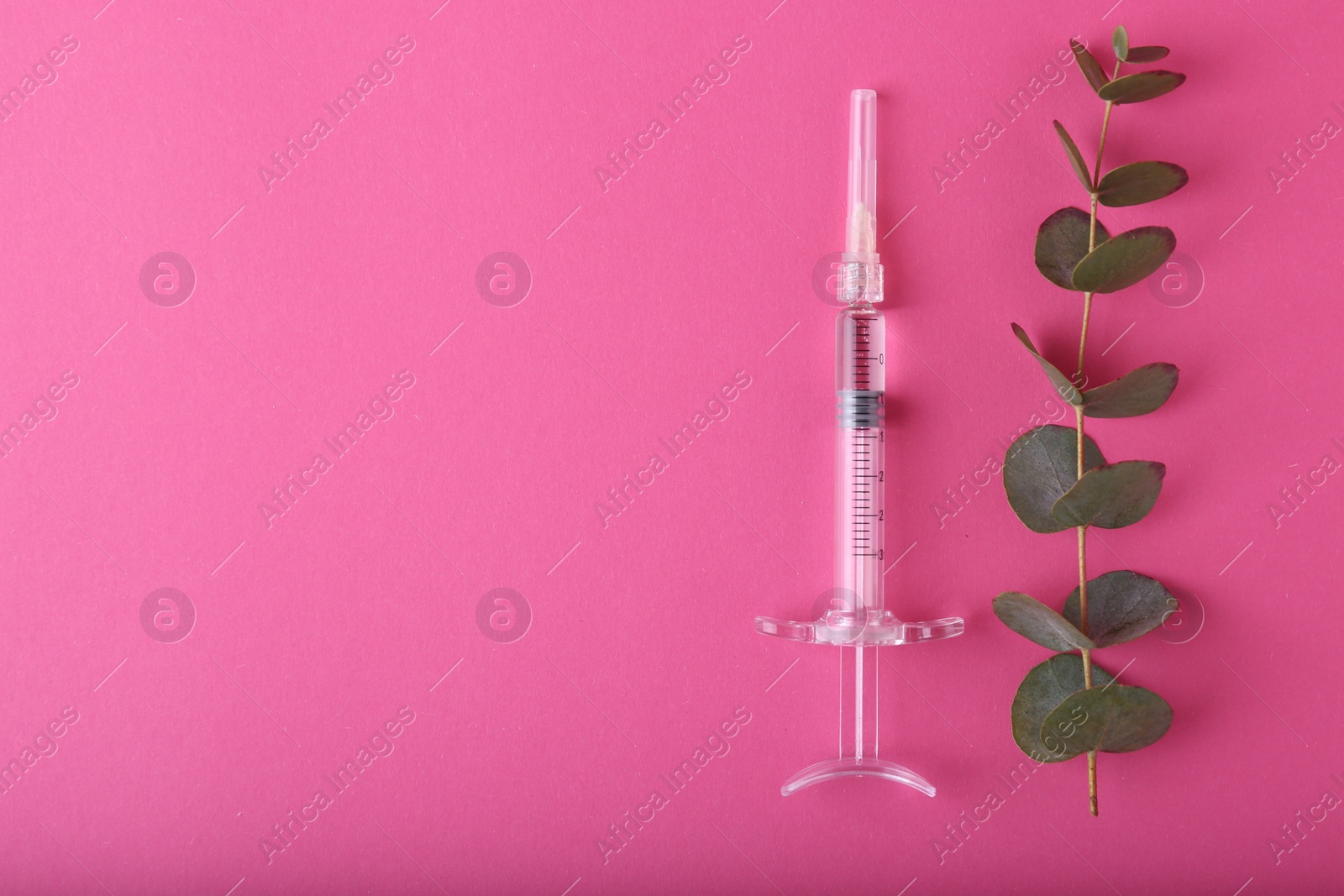 Photo of Cosmetology. Medical syringe and eucalyptus branch on pink background, flat lay. Space for text