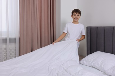 Photo of Boy changing bed linens in bedroom. Domestic chores