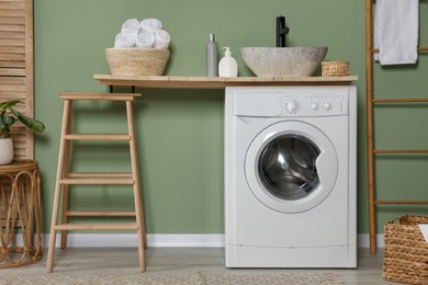 Photo of Stylish laundry room with functional washing machine. Interior design