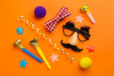 Flat lay composition with clown's accessories on orange background