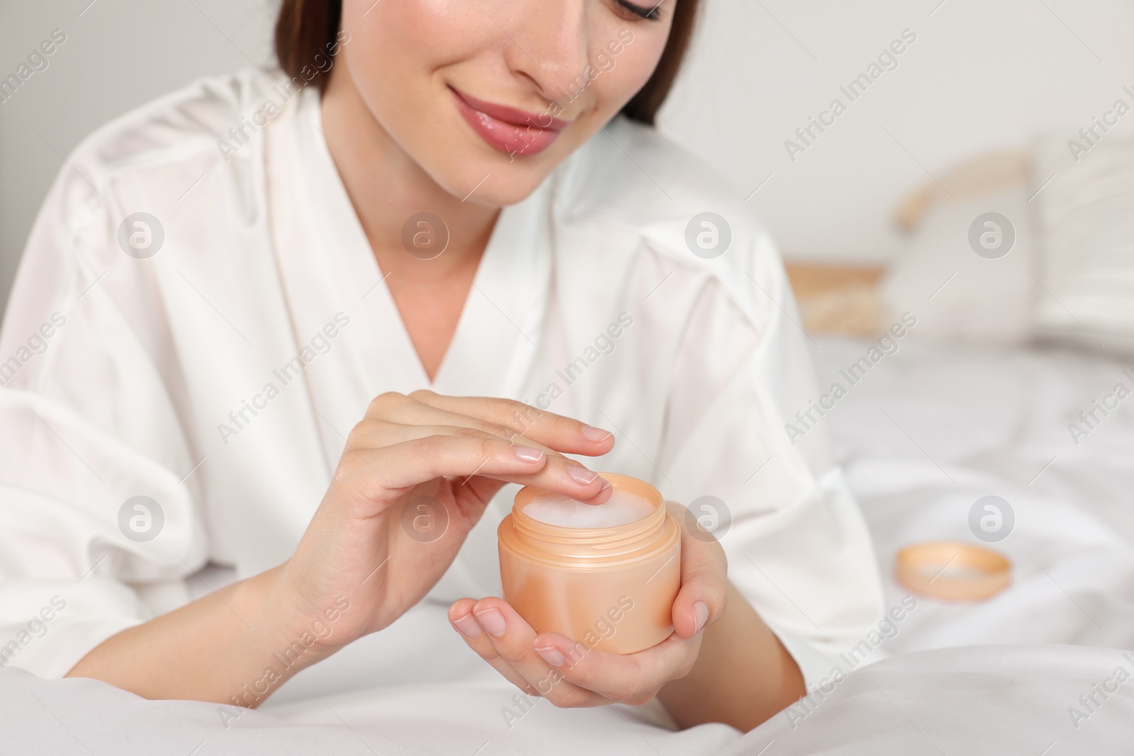 Photo of Woman taking hand cream from jar indoors, closeup