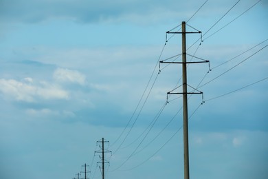 Photo of Telephone poles and wires against blue sky with clouds