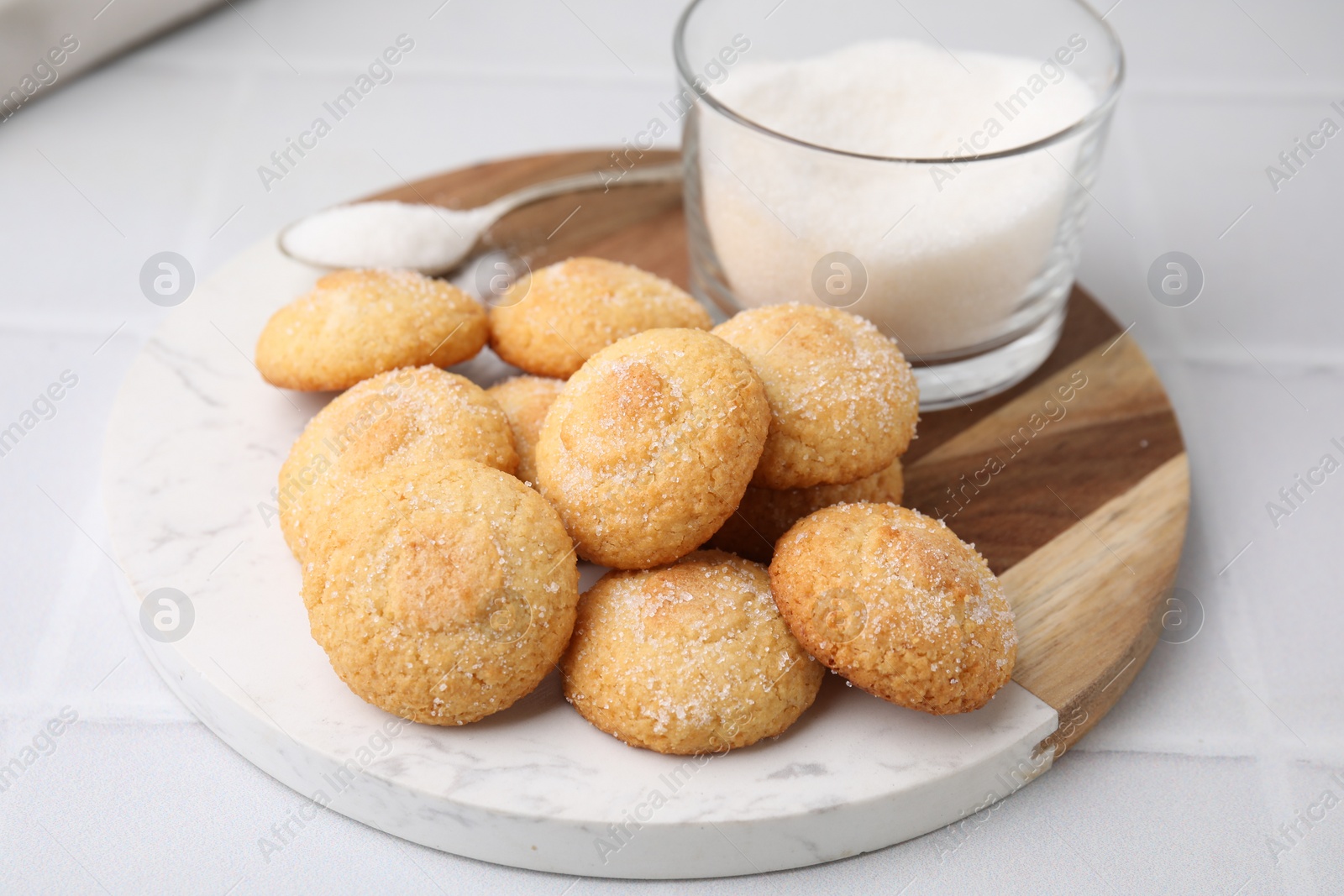 Photo of Tasty sweet sugar cookies and milk on white tiled table, closeup