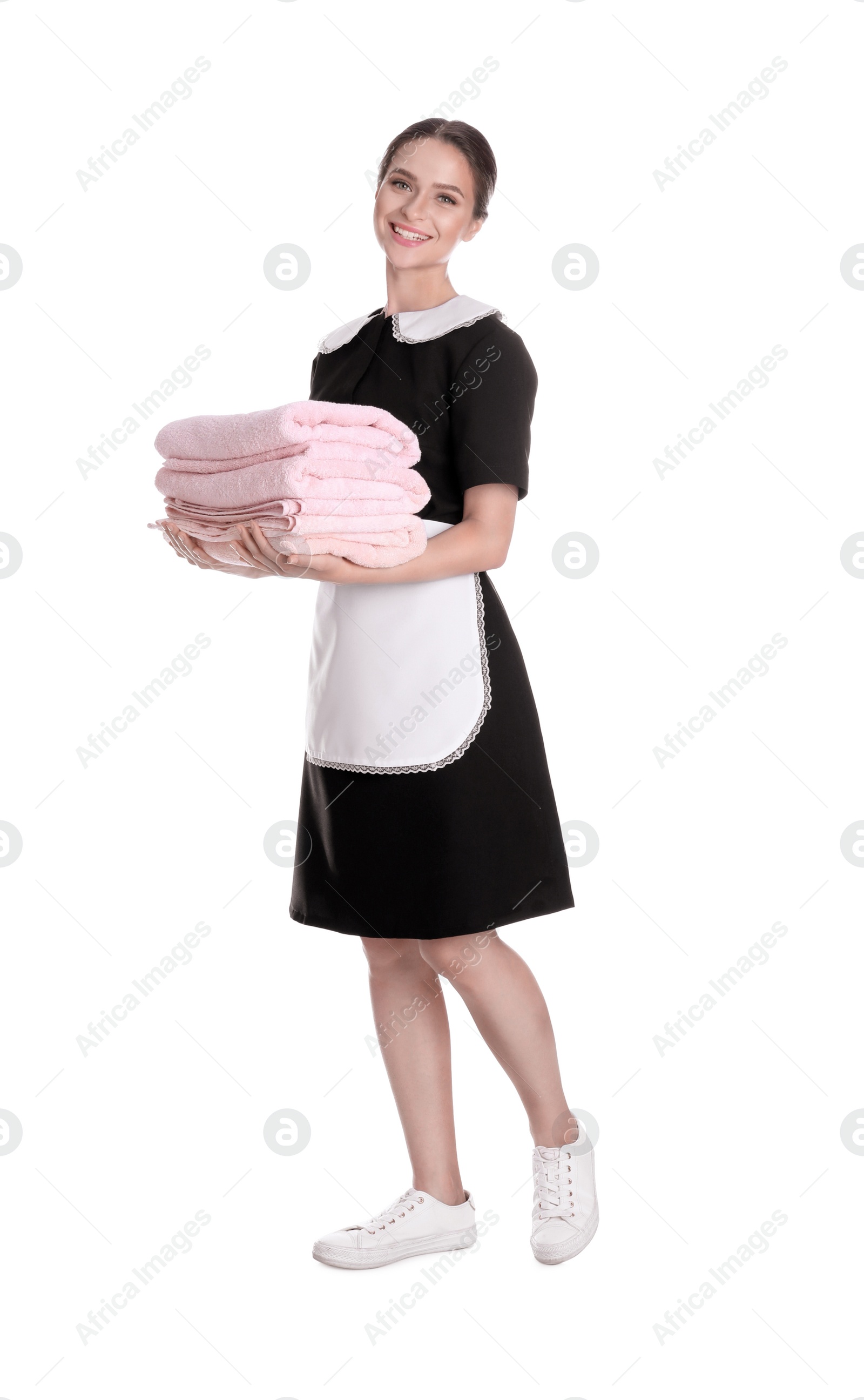 Photo of Young chambermaid holding stack of fresh towels on white background