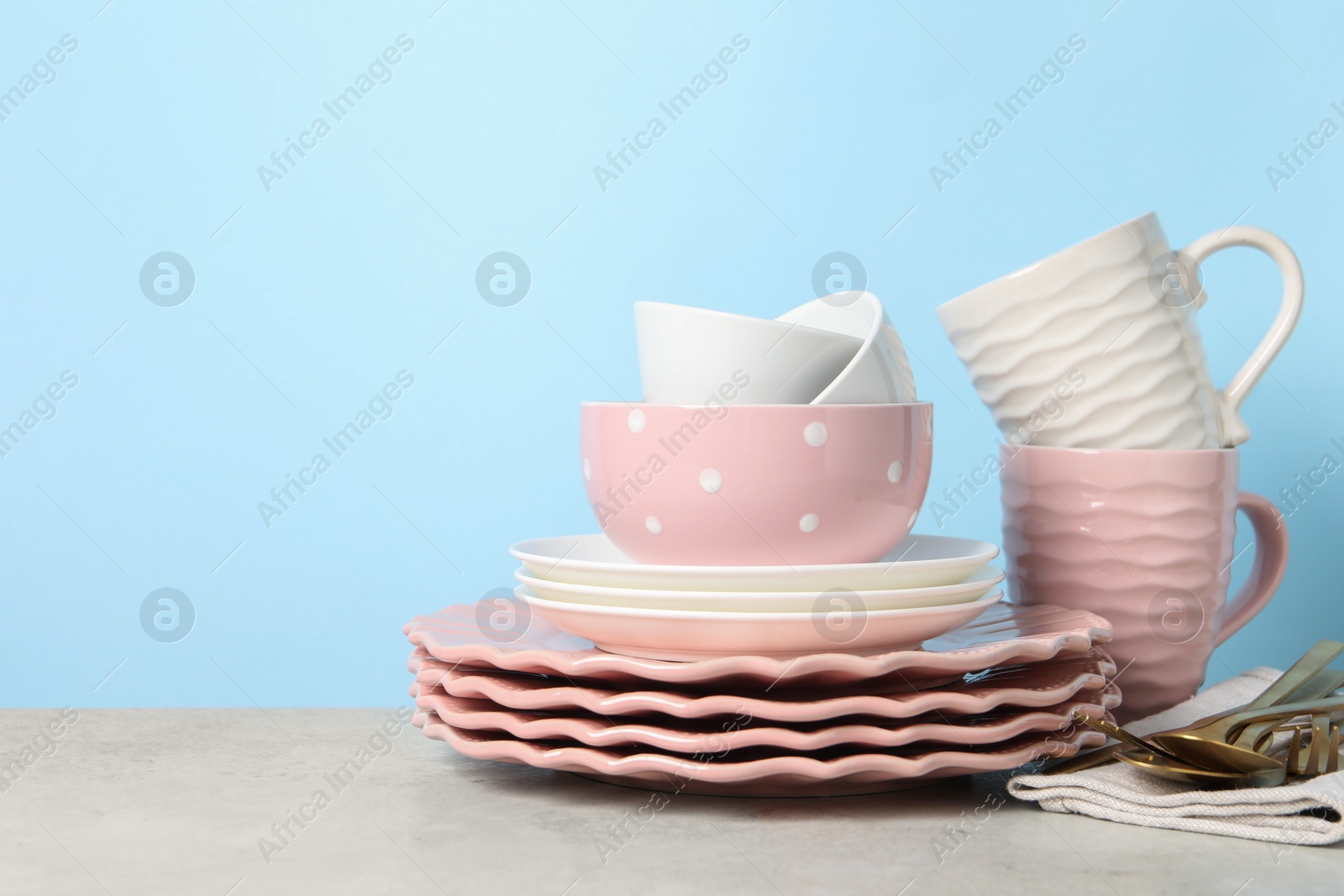 Photo of Beautiful ceramic dishware, cups and cutlery on light grey table, space for text