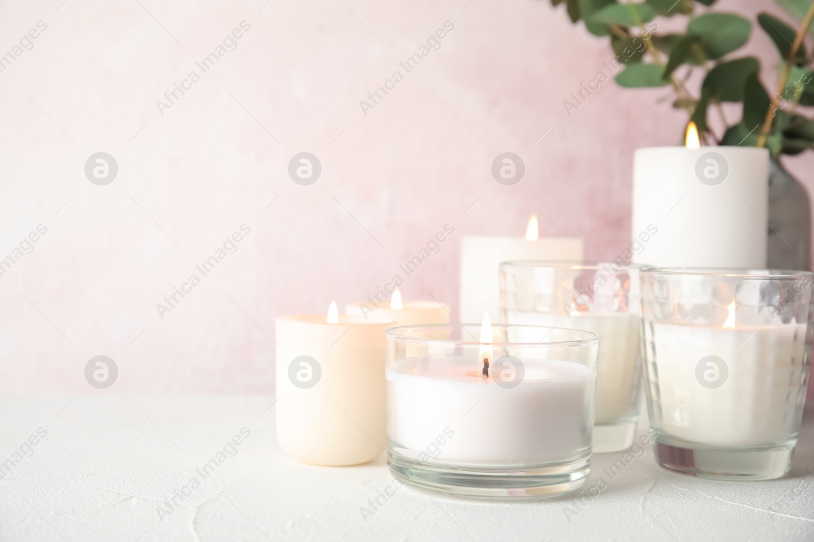 Photo of Burning aromatic candles in holders on table. Space for text