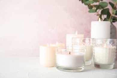 Burning aromatic candles in holders on table. Space for text