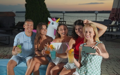 Happy people taking selfie at pool party in evening