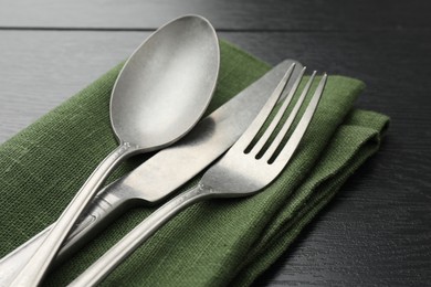 Stylish setting with cutlery and napkin on black wooden table, closeup