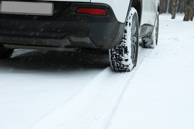 Car leaving tire tracks on snowy road outdoors