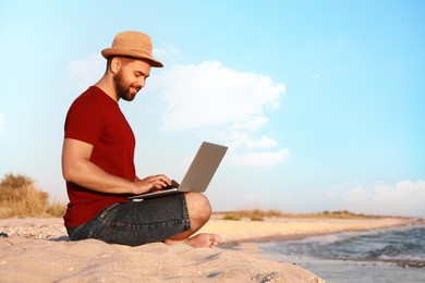 Man working with laptop on beach. Space for text