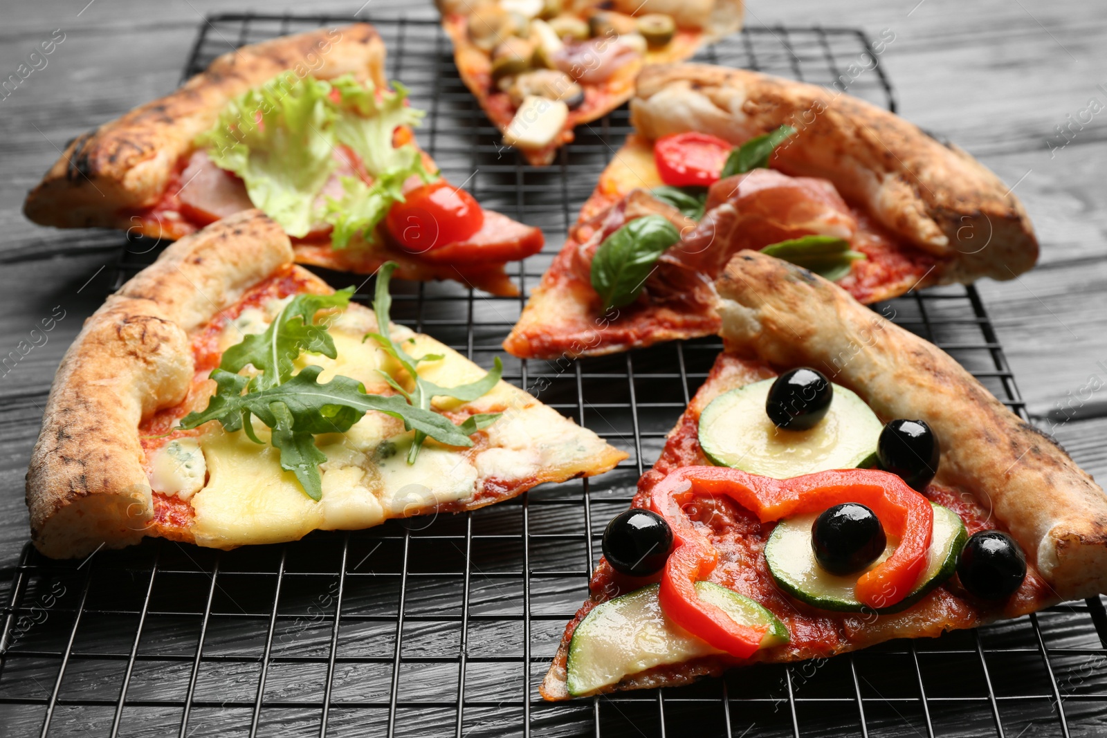 Photo of Slices of different delicious pizzas on grey wooden table, closeup