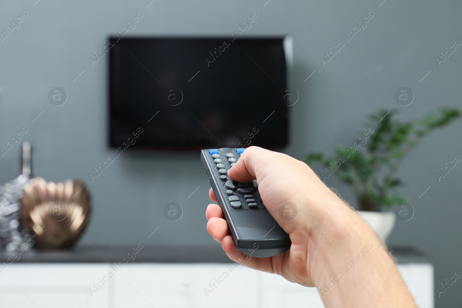 Photo of Man switching channels on plasma TV with remote control at home