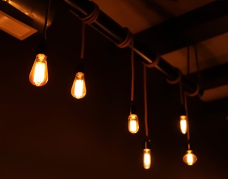 Glowing lamp bulbs in dark room. Interior element