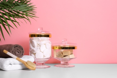 Photo of Composition of glass jar with cotton pads on table near pink wall. Space for text