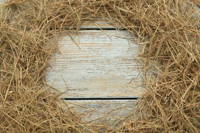 Photo of Frame of dried hay on light wooden background, flat lay. Space for text