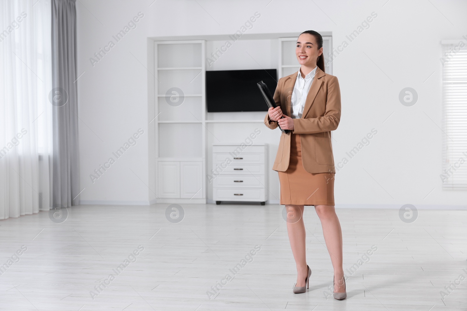 Photo of Happy real estate agent with leather portfolio in new apartment