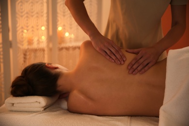 Photo of Young woman receiving back massage in spa salon