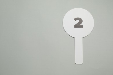 Photo of Auction paddle with number 2 on light grey background, top view. Space for text