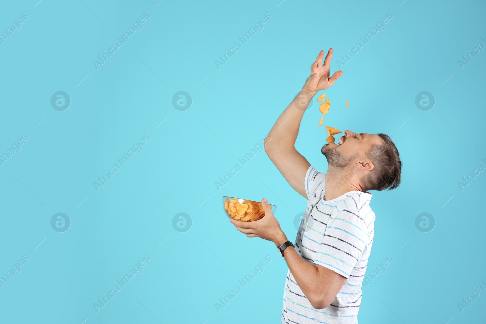 Photo of Man eating potato chips on color background. Space for text