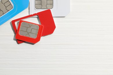 Photo of Different SIM cards on white wooden background, flat lay. Space for text
