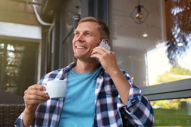 Photo of Man talking on smartphone in outdoor cafe