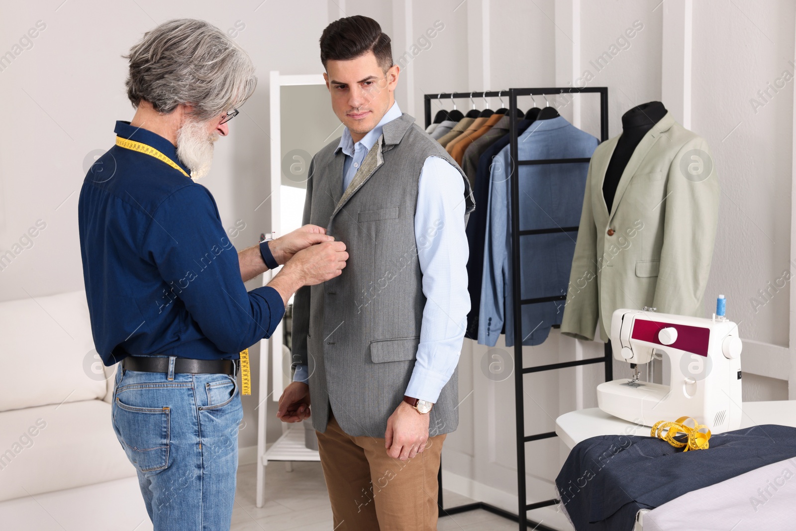 Photo of Professional tailor working with client in atelier