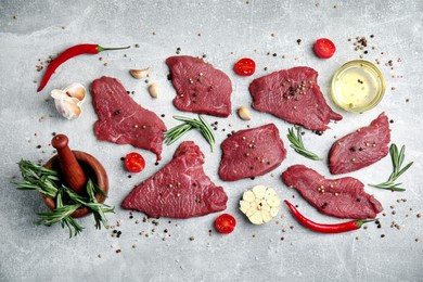 Photo of Fresh raw meat steaks and spices on light grey table, flat lay