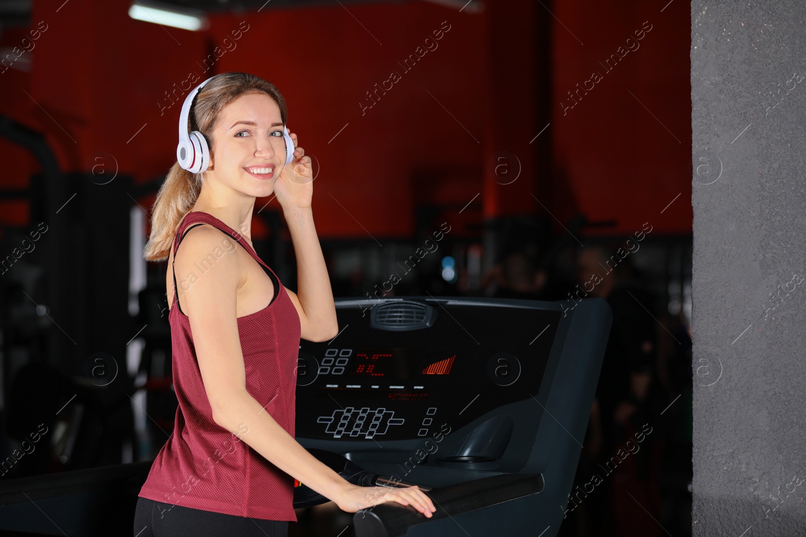 Photo of Young woman listening to music with headphones at gym