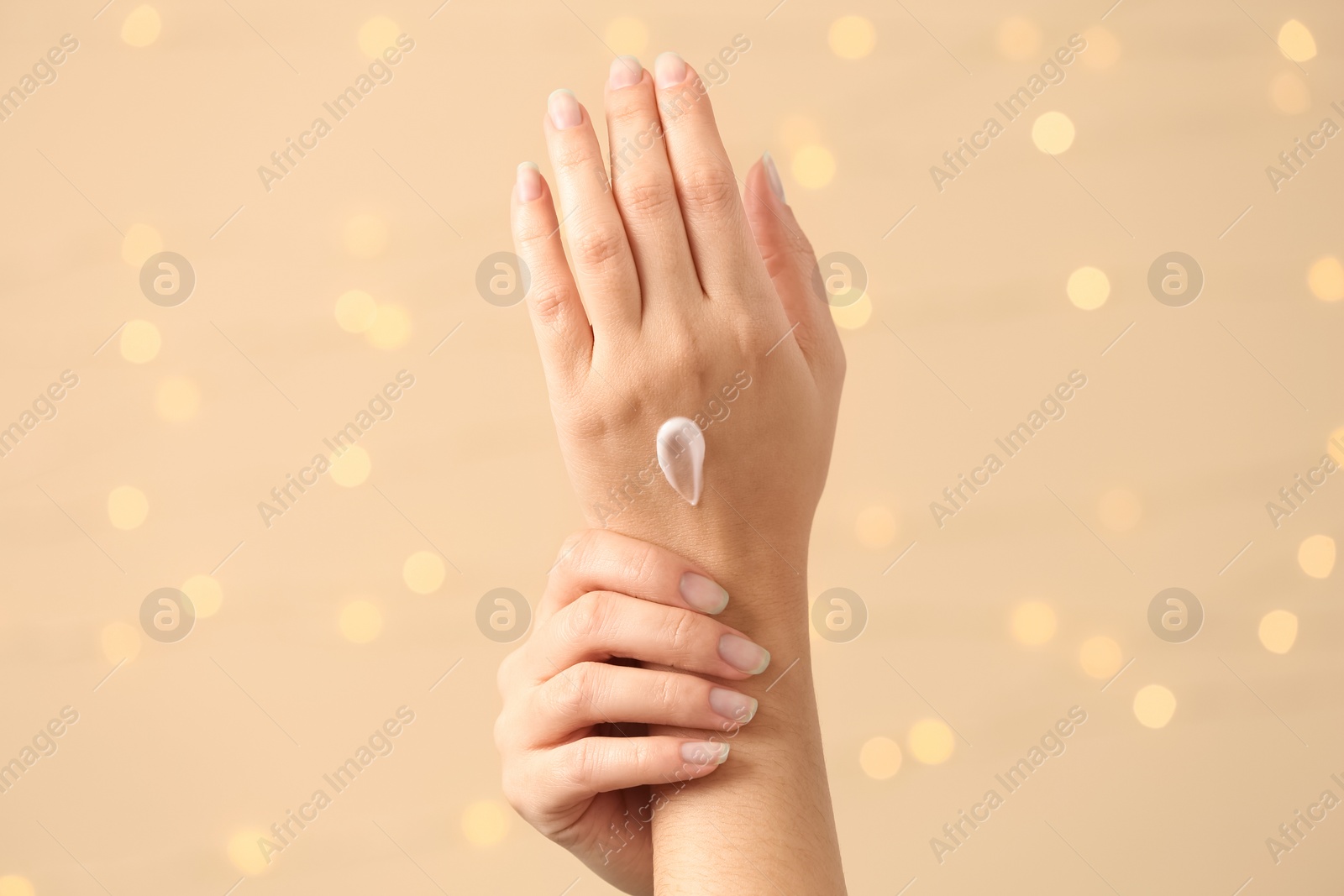 Photo of Woman applying hand cream on blurred background, closeup