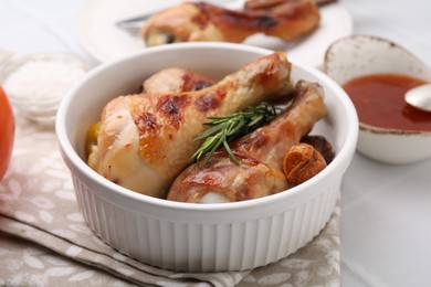Photo of Marinade, roasted chicken drumsticks, rosemary and tomatoes on white table, closeup