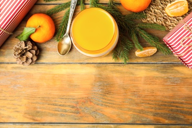 Photo of Delicious tangerine jelly and fir branches on wooden table, flat lay. Space for text