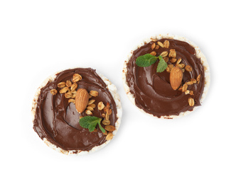 Photo of Puffed rice cakes with chocolate spread, nuts and mint isolated on white, top view