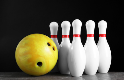 Photo of Yellow bowling ball and pins on grey stone table