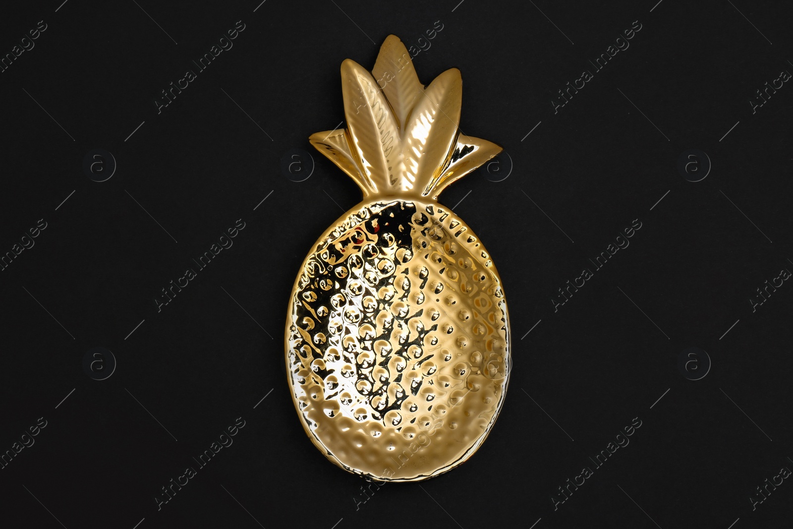 Photo of Gold pineapple shaped bowl on black background, top view