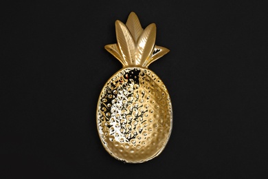 Photo of Gold pineapple shaped bowl on black background, top view