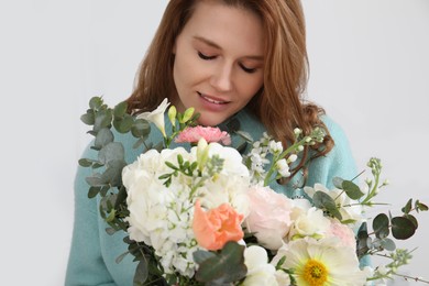 Photo of Beautiful woman with bouquet of flowers near white wall indoors, closeup