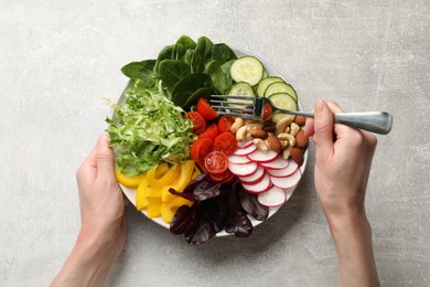 Balanced diet and vegetarian foods. Woman eating dinner at grey table, top view