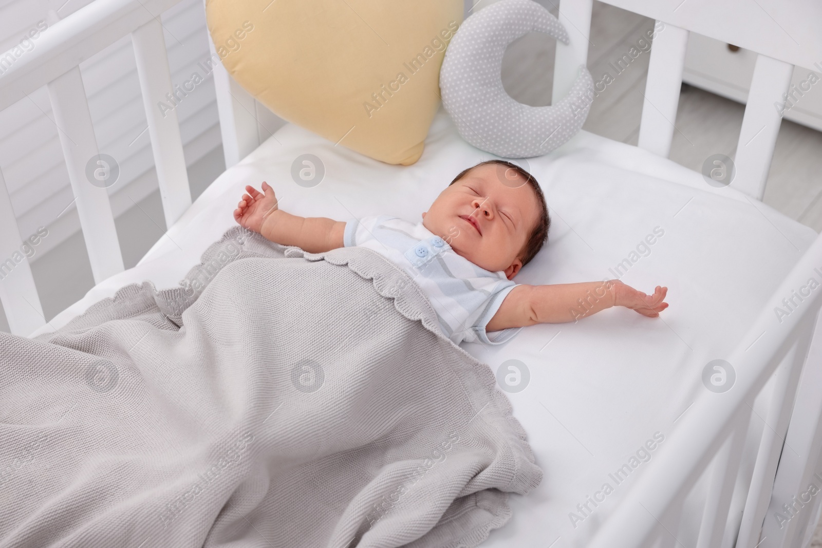 Photo of Cute newborn baby sleeping under blanket in crib at home