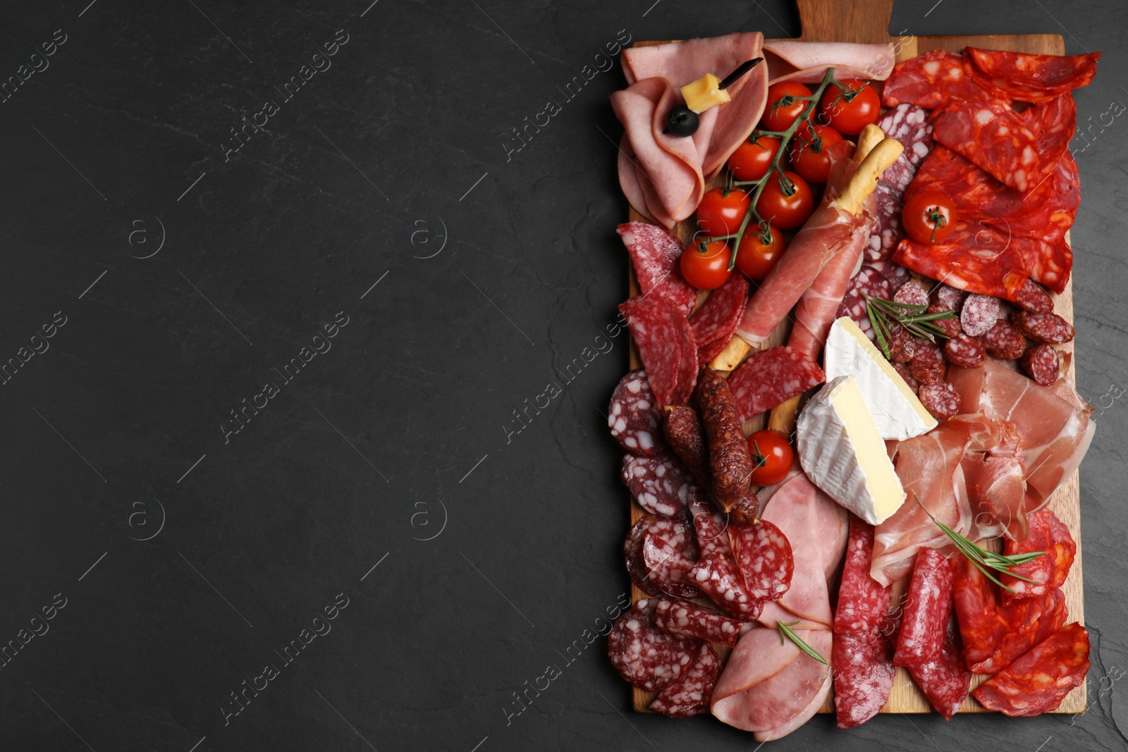 Photo of Tasty ham with other delicacies served on black table, top view. Space for text