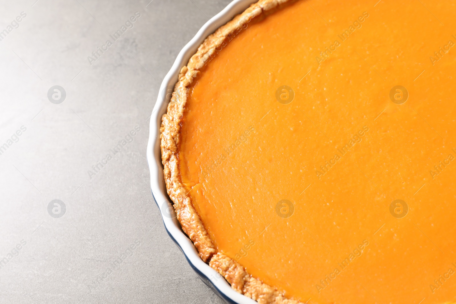 Photo of Fresh delicious homemade pumpkin pie on gray background. Space for text