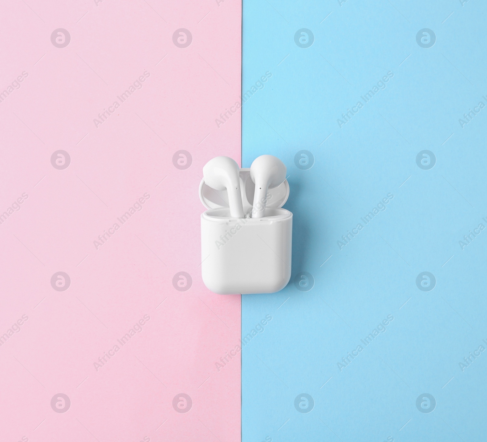 Photo of Modern wireless earphones in charging case on color background, top view