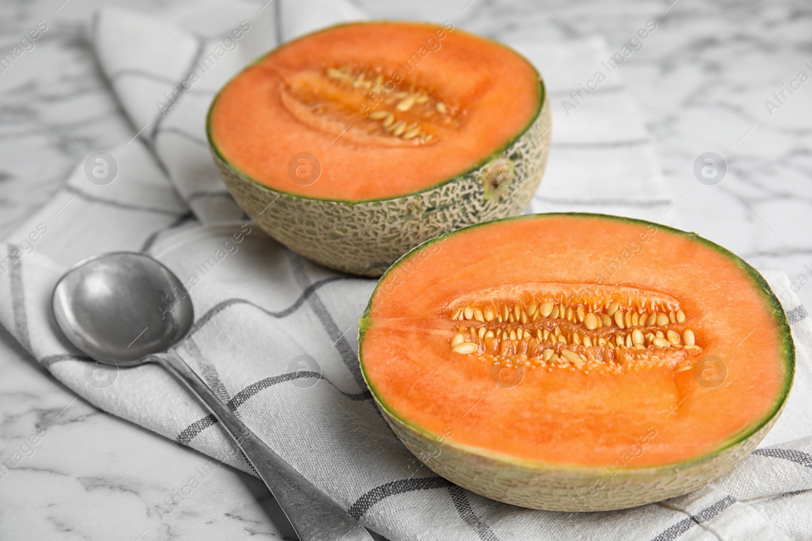 Photo of Cut ripe cantaloupe melon and spoon on white marble table